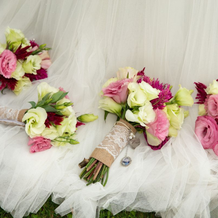 Lisianthus Bridal and Bridesmaids bouquets in hot pink and white set on the brides dress